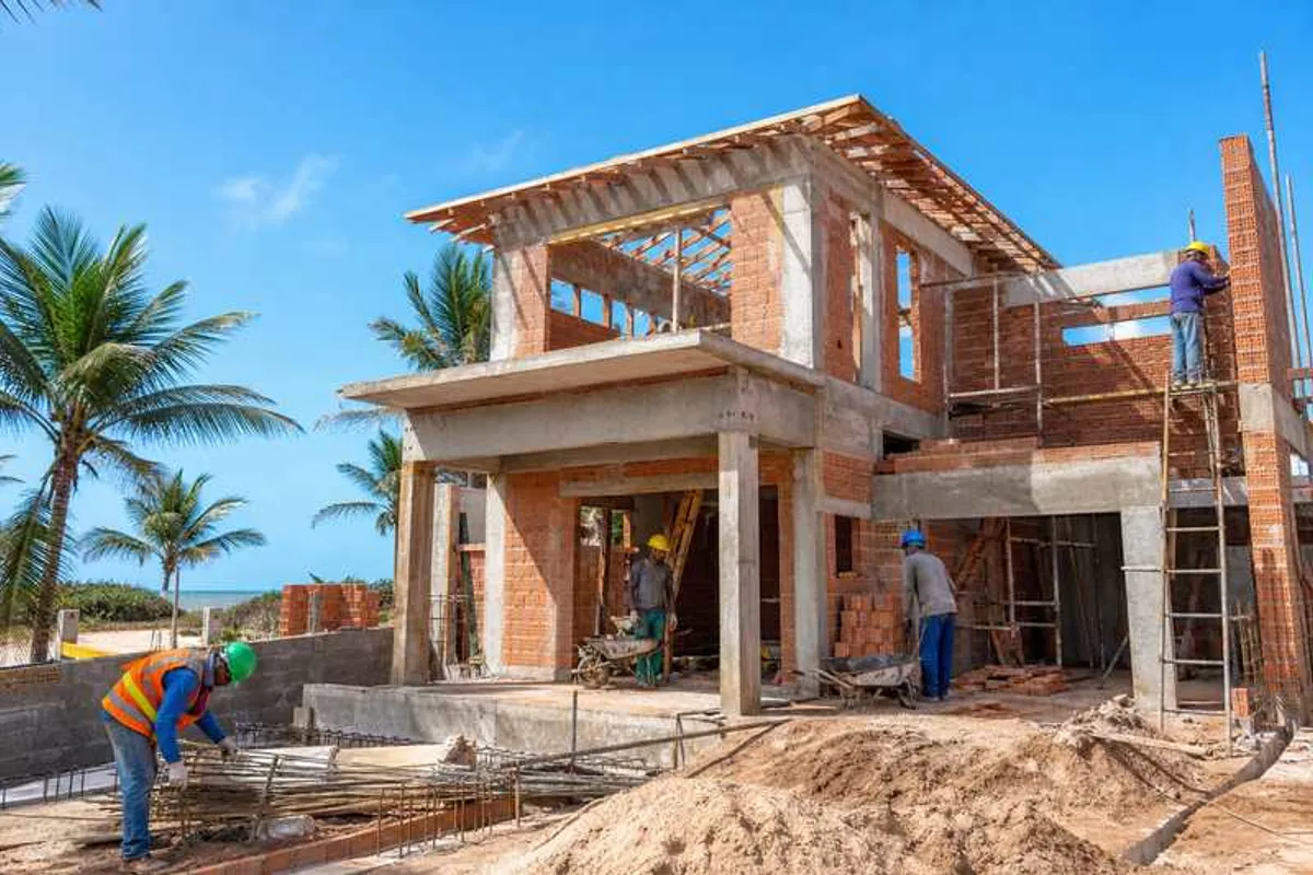 Casa em construção em bairro litorâneo de Canasvieiras com operários e estrutura de concreto